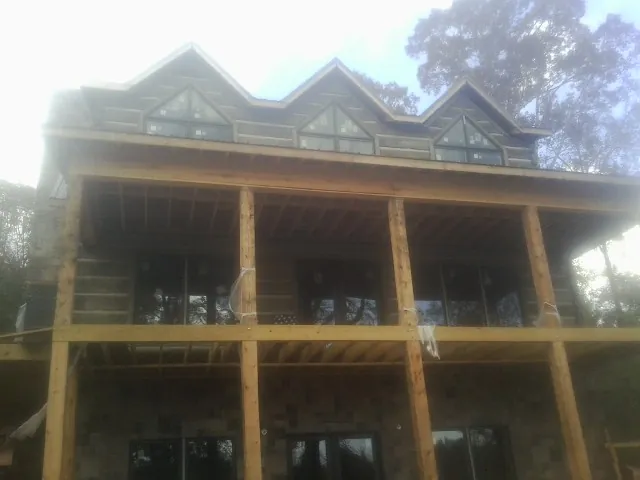 Dormers and porch framing on a large log home under construction — Roof Coating work by our crew in Blomkest