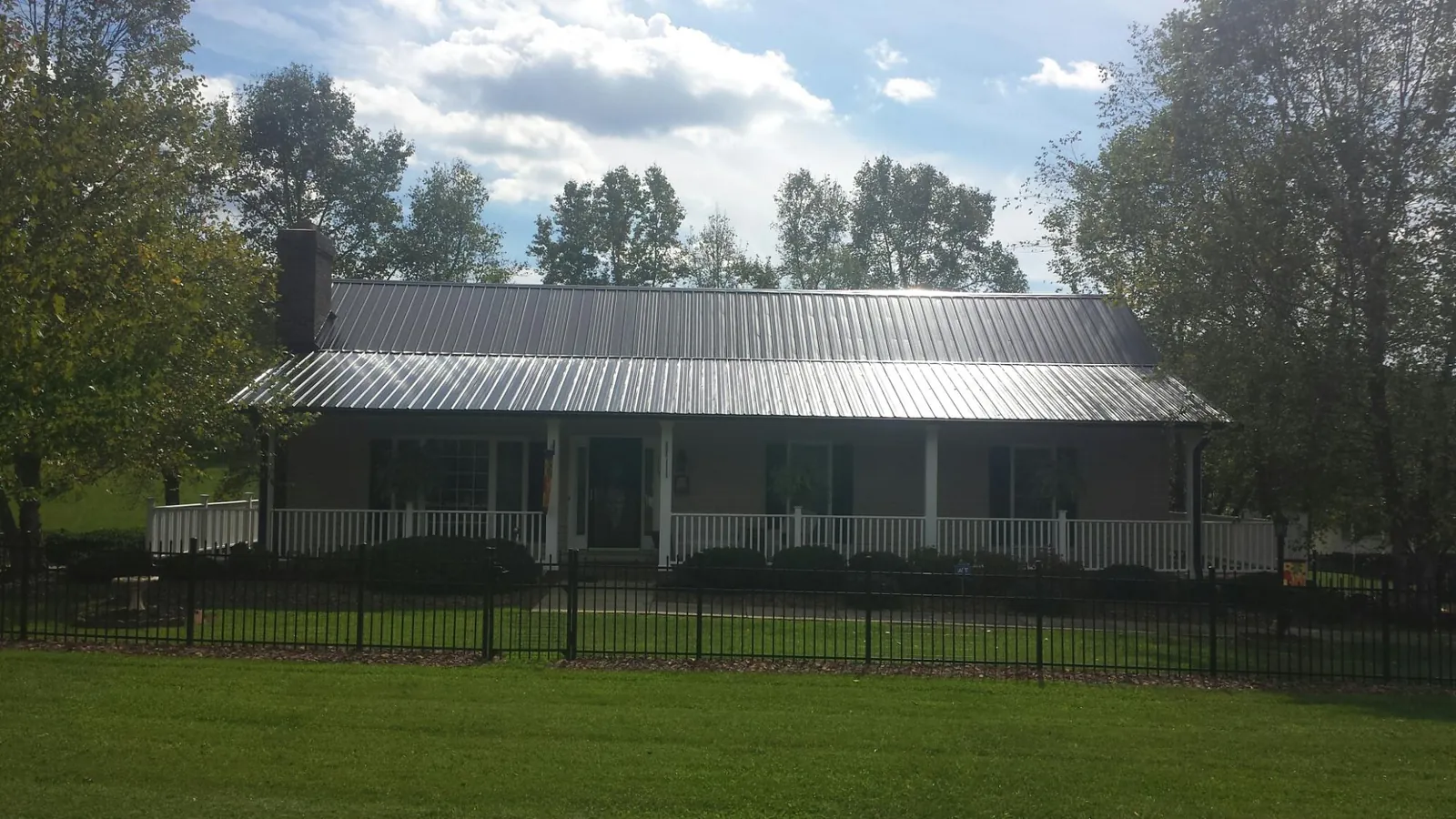 Gray metal roof on a brick ranch with a full width front porch — Gutter Guard Installation work by our crew in Blomkest